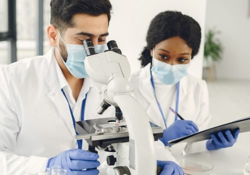 New test. Concentrated skilled researchers wearing uniform. Doing test, creating vaccine.